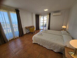 Habitació d'hotel amb un llit, una taula de treball, una cadira, una làmpada i vistes a l'exterior.