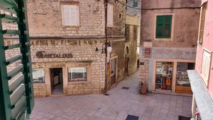 A narrow street with a shop named "METAL DUS" on the left, featuring a brick facade and a small entrance. - Rialto Luxury Apartment (Sibenik)