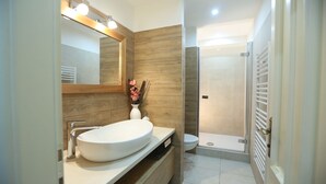 A modern bathroom with a wooden vanity, a large mirror, a toilet, and a shower area. - Rialto Luxury Apartment (Sibenik)