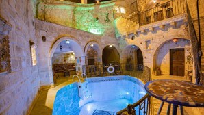 A historic building with a swimming pool, stone arches, and a balcony with metal railings. - Royal Cave Hotel (Ürgüp)