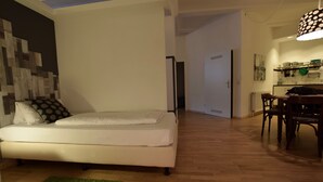 A modern living room with a sofa, a green rug, and a dining area with a table and chairs. - Loft 1. 4 in the heart of Berlin (Bezirk Friedrichshain-Kreuzberg)