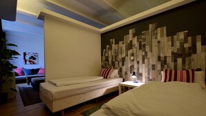 A modern hotel room with a large bed, a smaller sofa, a desk with a lamp, and a decorative wall panel. - Loft 1. 4 in the heart of Berlin (Bezirk Friedrichshain-Kreuzberg)