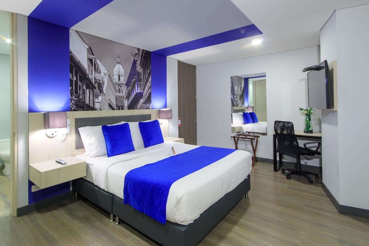 A modern hotel room with a large bed, bedside tables, a desk, and a chair.