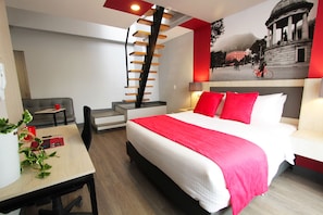 A modern hotel room with a large bed, a staircase, a desk, and a dining area. - GIO Suites Bogota (Bogotá)