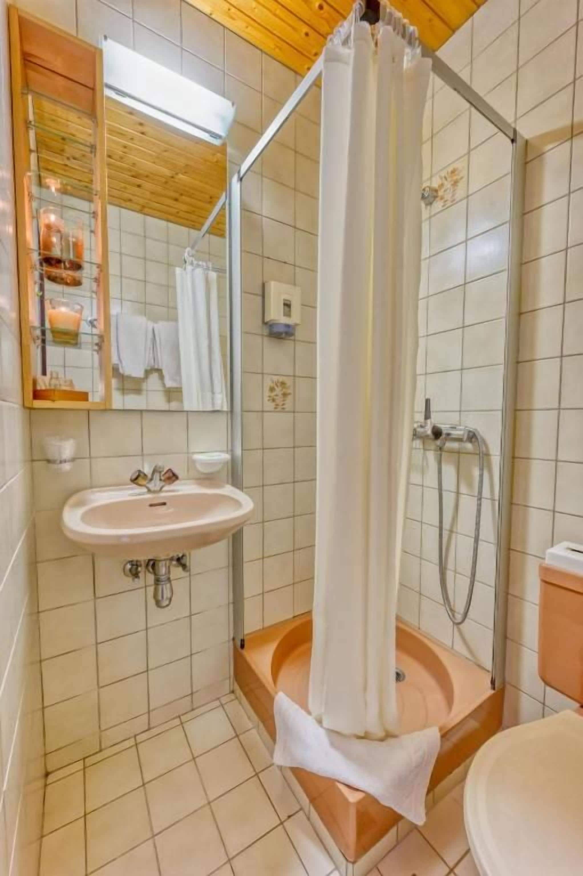 Un baño con ducha, lavamanos y espejo.