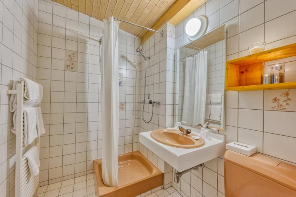 A bathroom with a shower, sink, mirror, and towel rack.