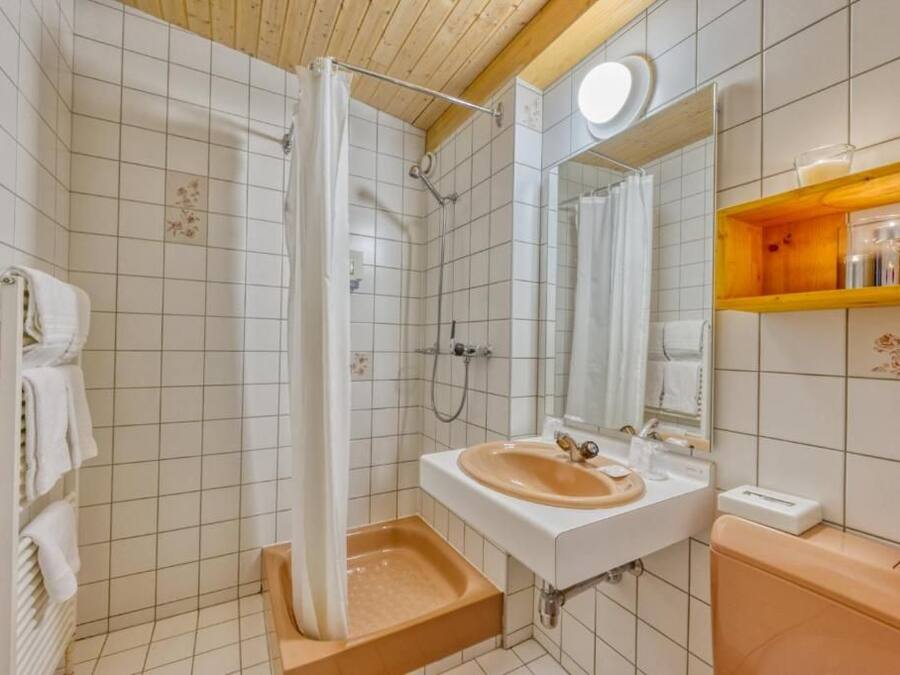 A bathroom with a shower, sink, mirror, and towel rack.