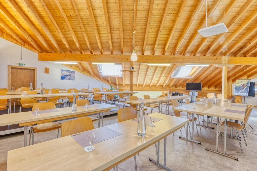 Un salón de conferencias con mesas largas, sillas y techo de madera.