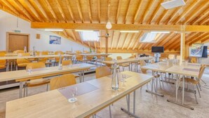 A conference room with long tables, chairs, and a wooden ceiling. - Hôtel Les Sources (Ormont-Dessus)