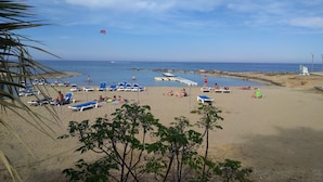 Ein Strand mit Liegestühlen und einem kleinen Poolbereich.
