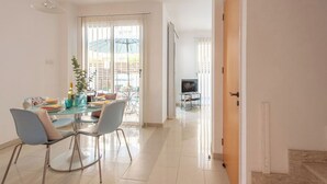 Ein modernes Wohnzimmer mit Essbereich, Fernseher und Blick ins Freie.