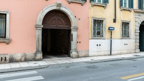 Un bâtiment doté d’une entrée arquée remarquable, situé sur une rue, et devant lequel se trouve un panneau de signalisation bleu.