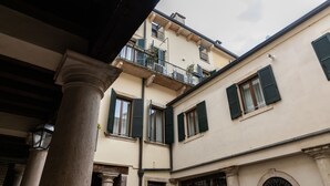 Un bâtiment doté d’un balcon, de colonnes et d’une fenêtre avec des volets.