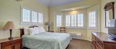A bedroom with a bed, nightstands, a dresser, a ceiling fan, and windows with blinds.