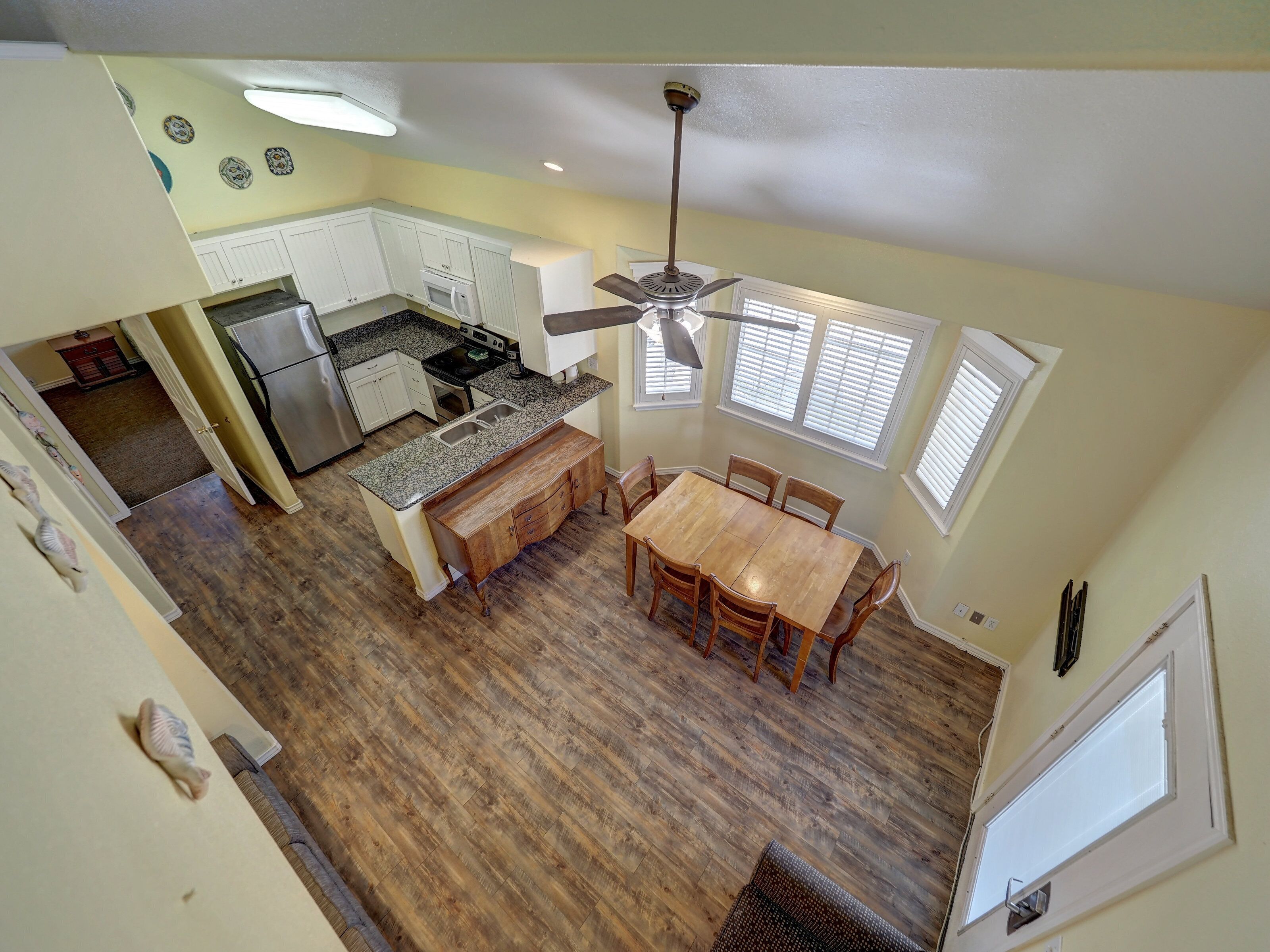 A kitchen with a dining area, wooden flooring, and a ceiling fan.