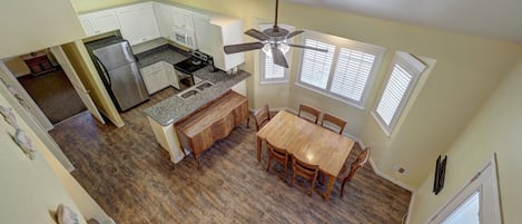 A kitchen with a dining area, wooden flooring, and a ceiling fan.