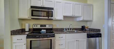 A kitchen with white cabinets, a microwave, an oven, a sink, and a dishwasher.