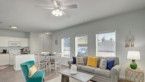 A modern living room with a grey sofa, teal armchair, and a coffee table. - Seashell Village Resort near the beach with kitchens (Port Aransas)