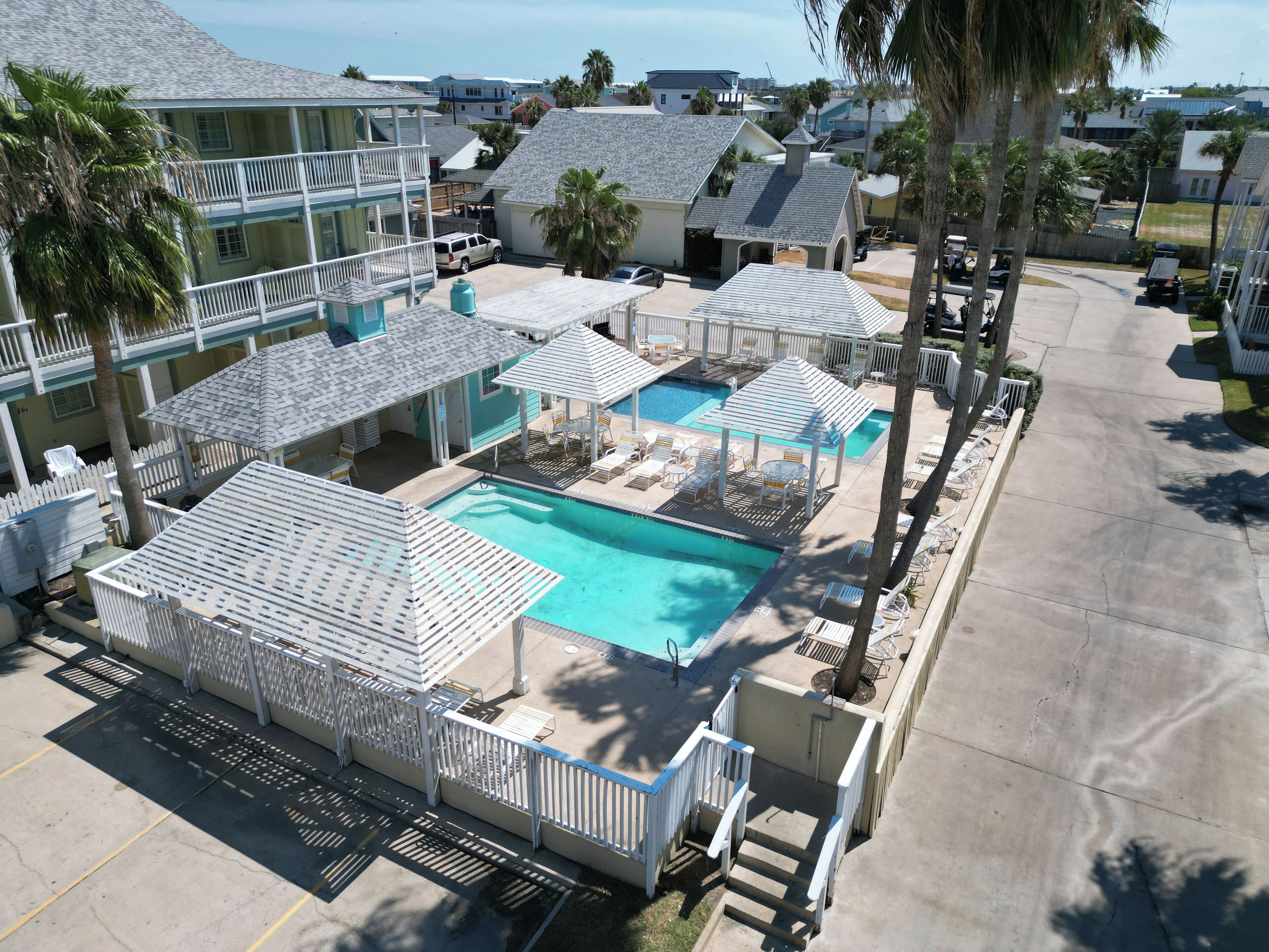 A resort with a swimming pool, lounge chairs, and umbrellas.
