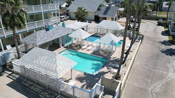 A resort with a swimming pool, lounge chairs, and umbrellas.