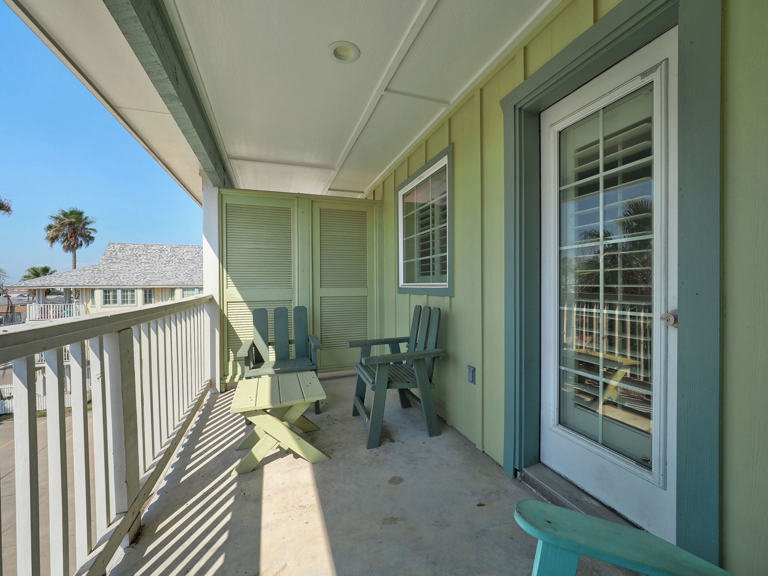 A covered porch with a concrete floor, green chairs, and a picnic table.