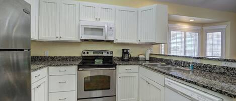 A kitchen with white cabinets, a stainless steel refrigerator, a microwave, an oven, and a dishwasher.