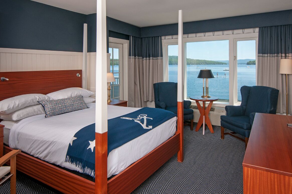 Habitación de hotel con una cama grande, dos sillas, un escritorio y vista al agua.