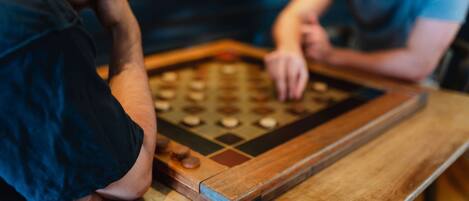 Two people playing a wooden board game at a table.