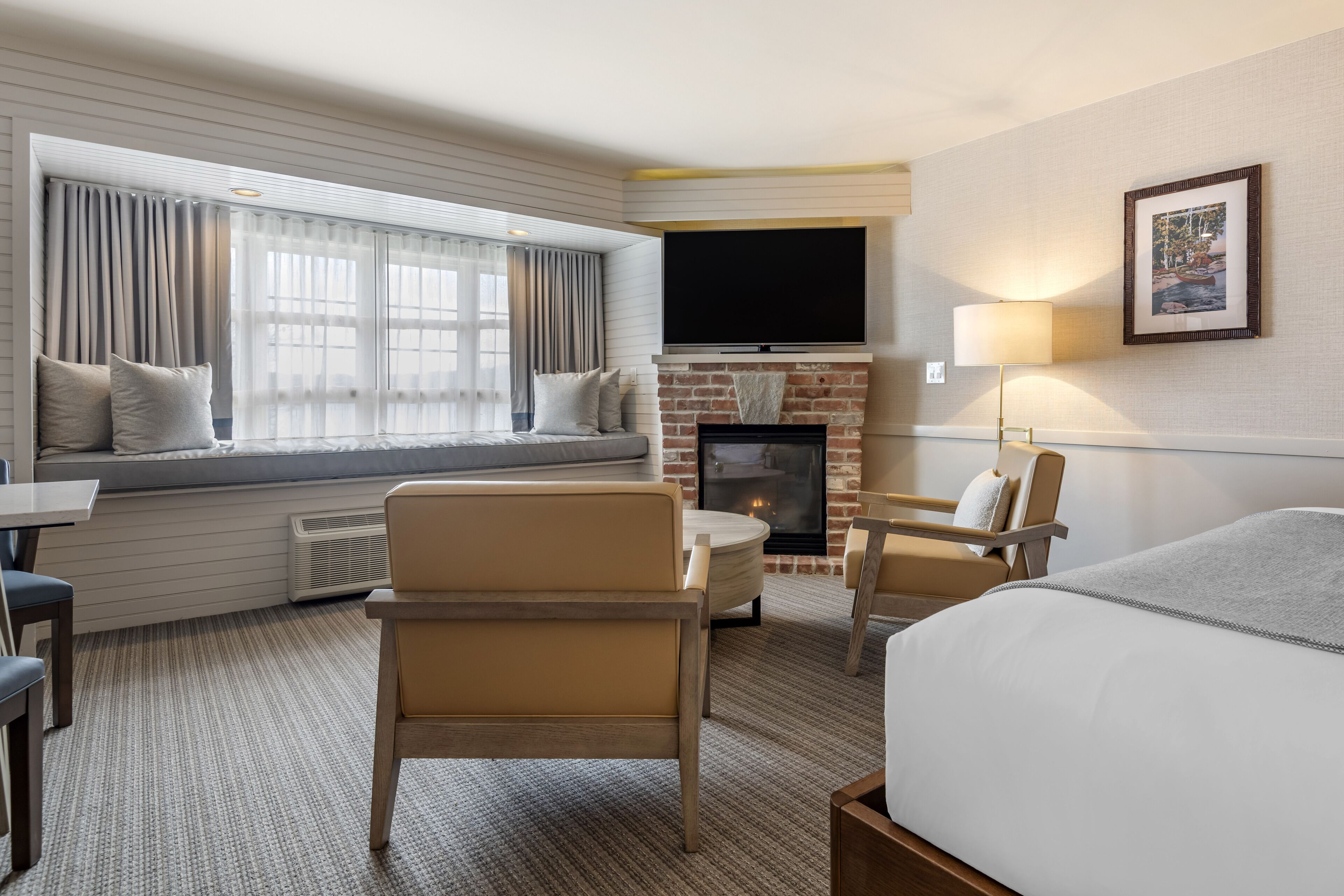 Quarto de hotel com uma grande janela, lareira, TV de tela plana e uma cama.