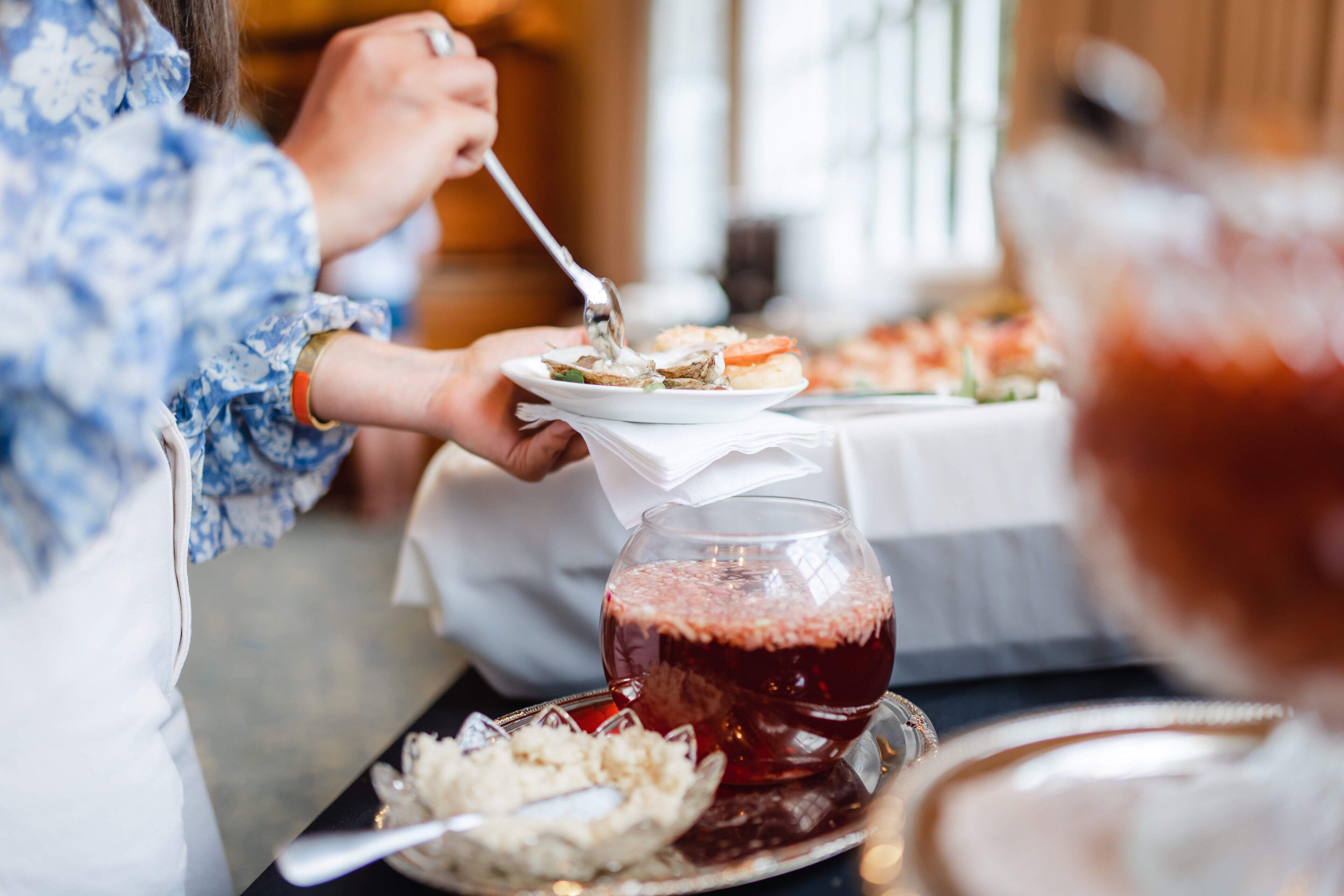 A dining table with plates of food and a glass of red beverage.