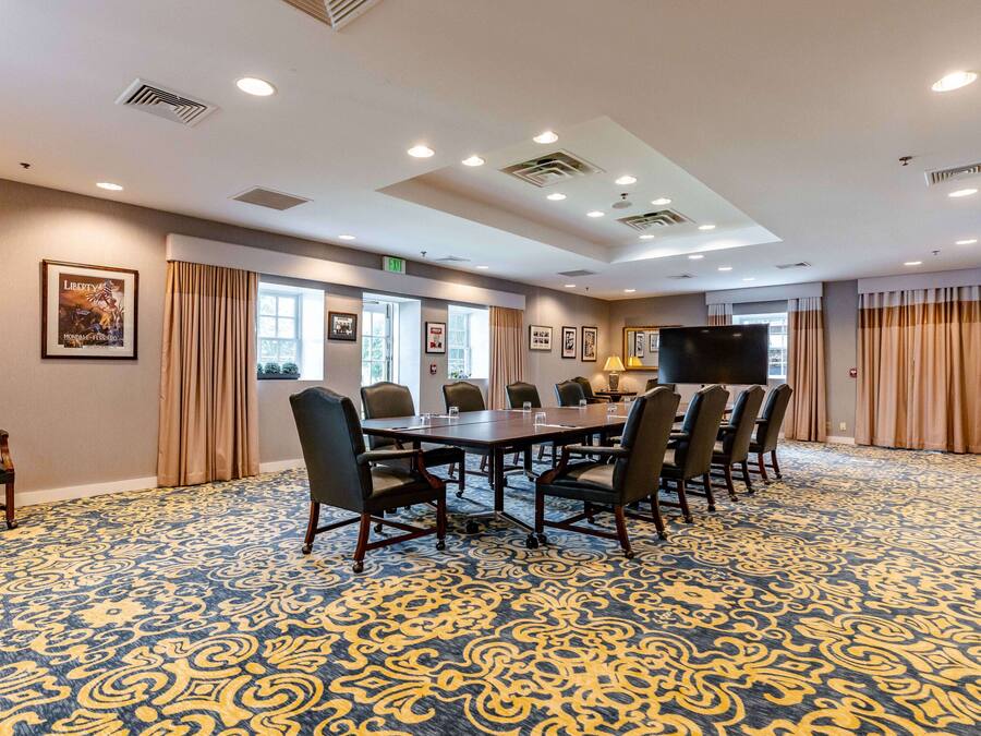 A conference room with a large table, chairs, and a television.