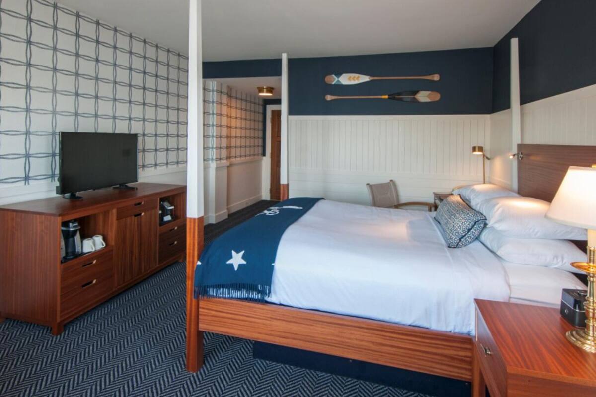 A hotel room with a bed, a TV, a wooden dresser, and a wall with two paddles.