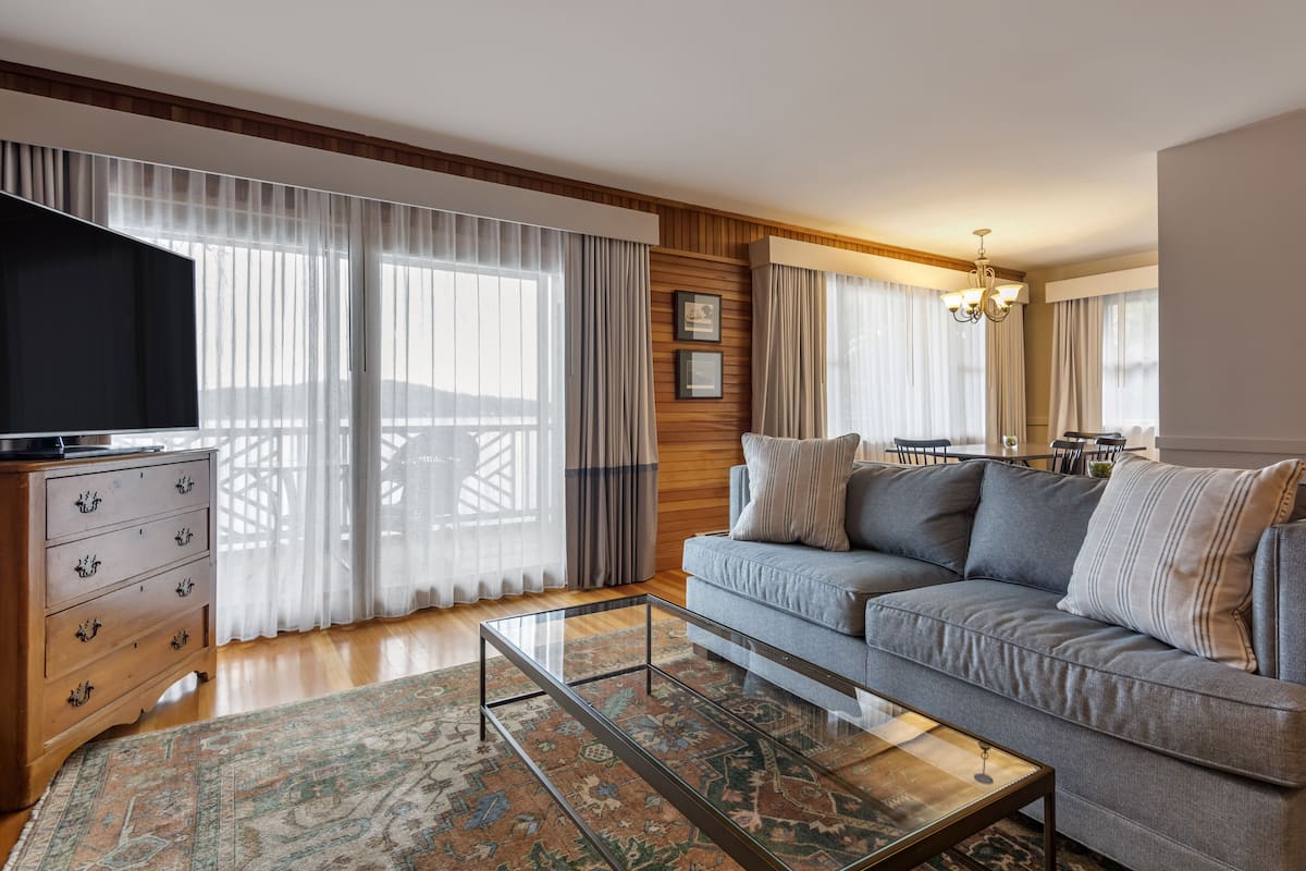 A living room with a sofa, a glass coffee table, a wooden dresser, and a TV.