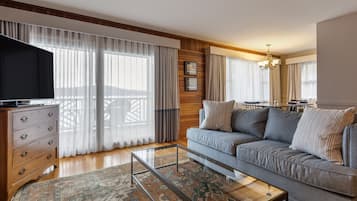 A living room with a sofa, a glass coffee table, a wooden dresser, and a TV.