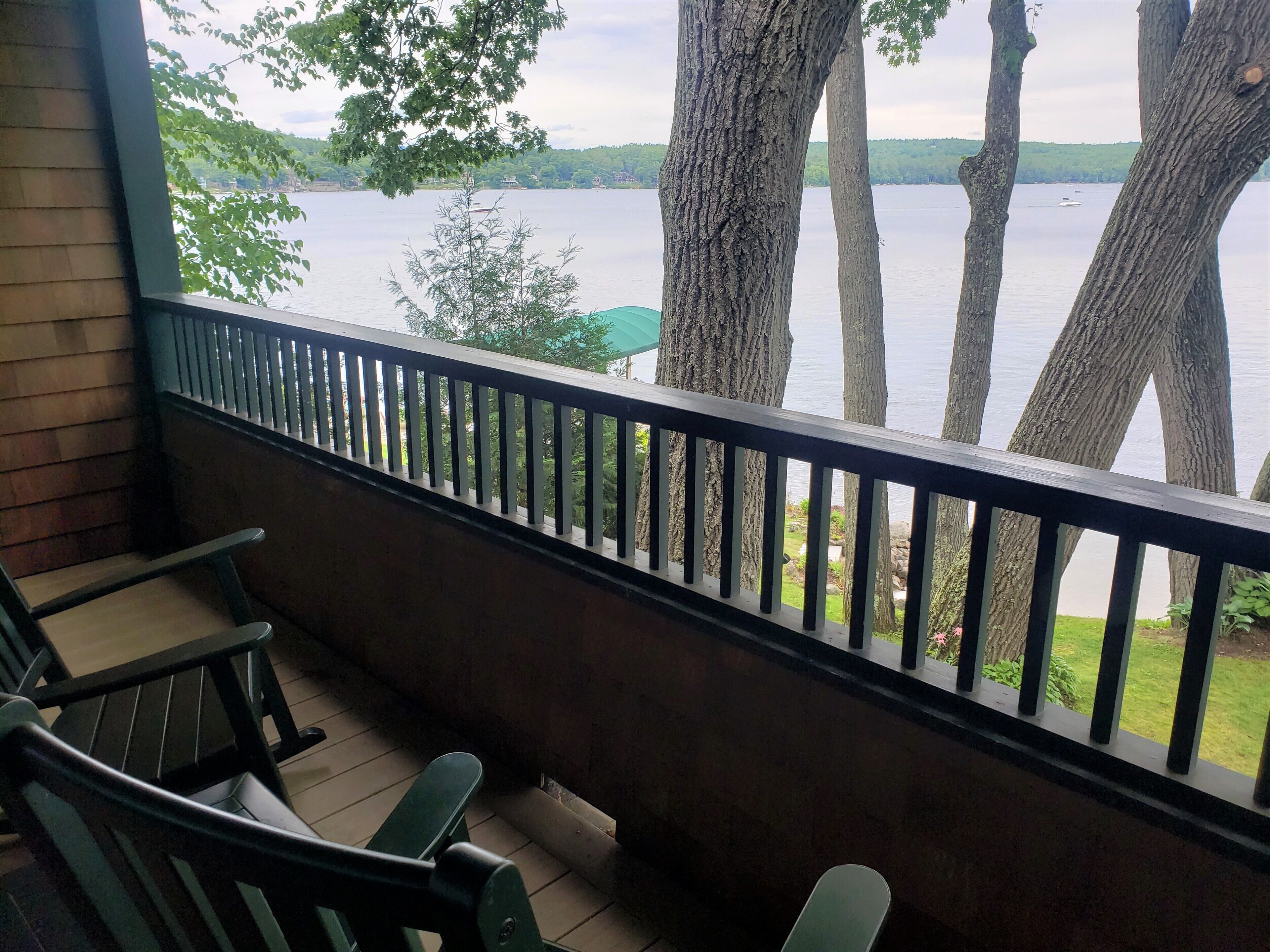 Un balcon donnant sur un lac, avec des chaises en bois et une balustrade.