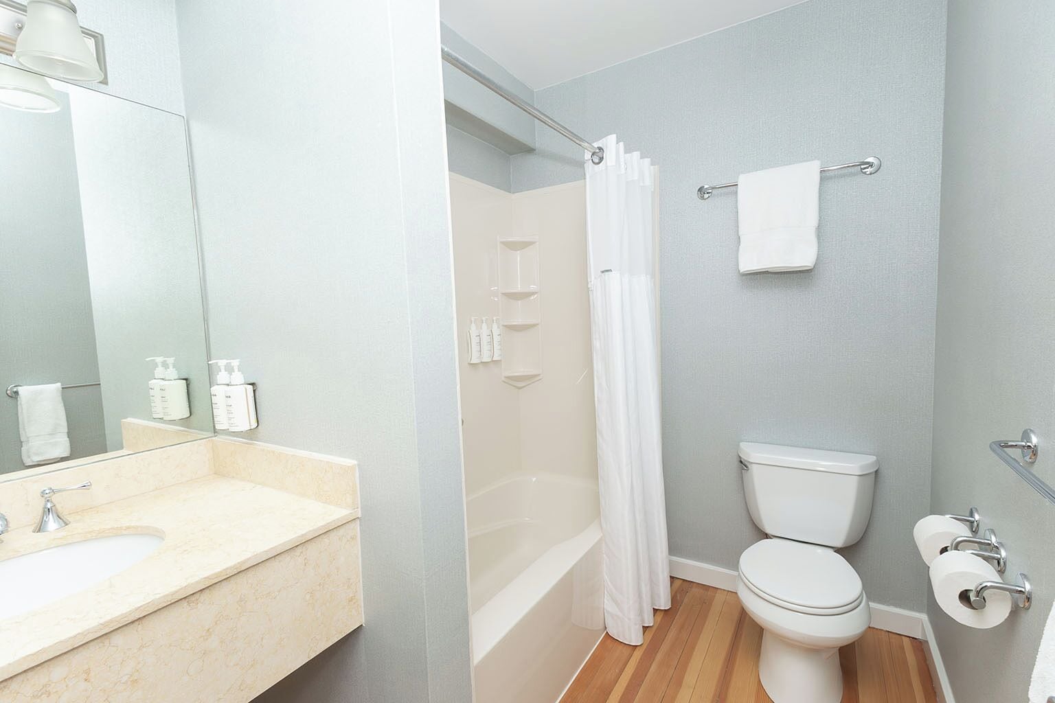 A modern bathroom with a sink, mirror, toilet, and shower.