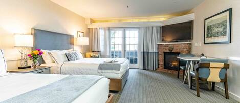 Une chambre d’hôtel avec deux lits, une cheminée, une télévision et un coin repas.