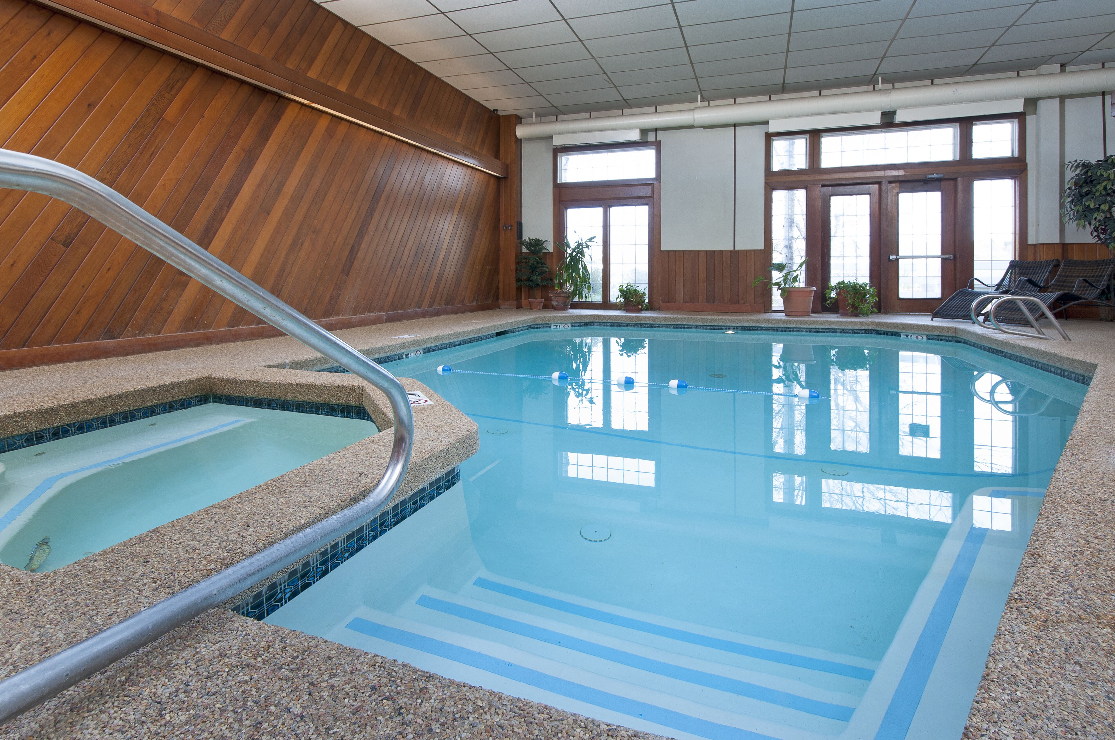 An indoor swimming pool with a wooden wall, a tiled floor, and a clear view of the pool area.
