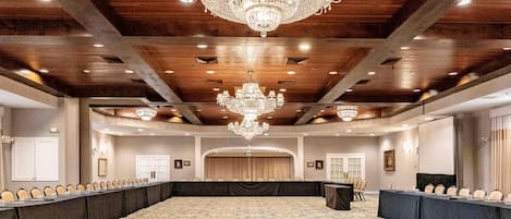 Uma sala de conferências ampla com uma mesa comprida, várias cadeiras e um candelabro.