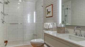 A modern bathroom with a glass-enclosed shower, a white toilet, a vanity with a mirror, and a towel rack.