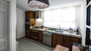 Eine moderne Küche mit Holzausstattung, einem Einbauofen, einem Geschirrspüler und einem großen Fenster.