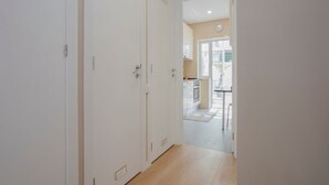 En hall med vita dörrar som leder in till ett köksområde.