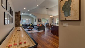 A spacious living room with a shuffleboard table, a large sofa set, and a dining area. - AC, Batman Arcade, Shuffleboard, 1GB Wifi, Walk to Heavenly/ Lake – Tahoe Woods Retreat (South Lake Tahoe)