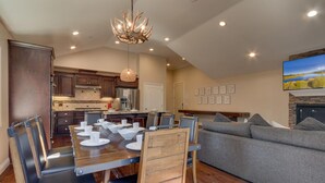 A modern kitchen with dark wood cabinets, a stainless steel refrigerator, and a dining area with a wooden table and chairs. - AC, Batman Arcade, Shuffleboard, 1GB Wifi, Walk to Heavenly/ Lake – Tahoe Woods Retreat (South Lake Tahoe)