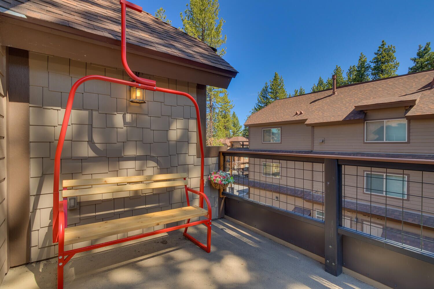 A balcony with a red metal chair, a small table, and a flower pot.