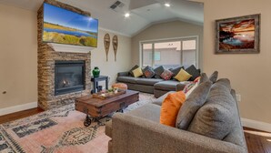 A living room with a stone fireplace, a large flat-screen TV, a sofa, and a coffee table. - AC, Batman Arcade, Shuffleboard, 1GB Wifi, Walk to Heavenly/ Lake – Tahoe Woods Retreat (South Lake Tahoe)