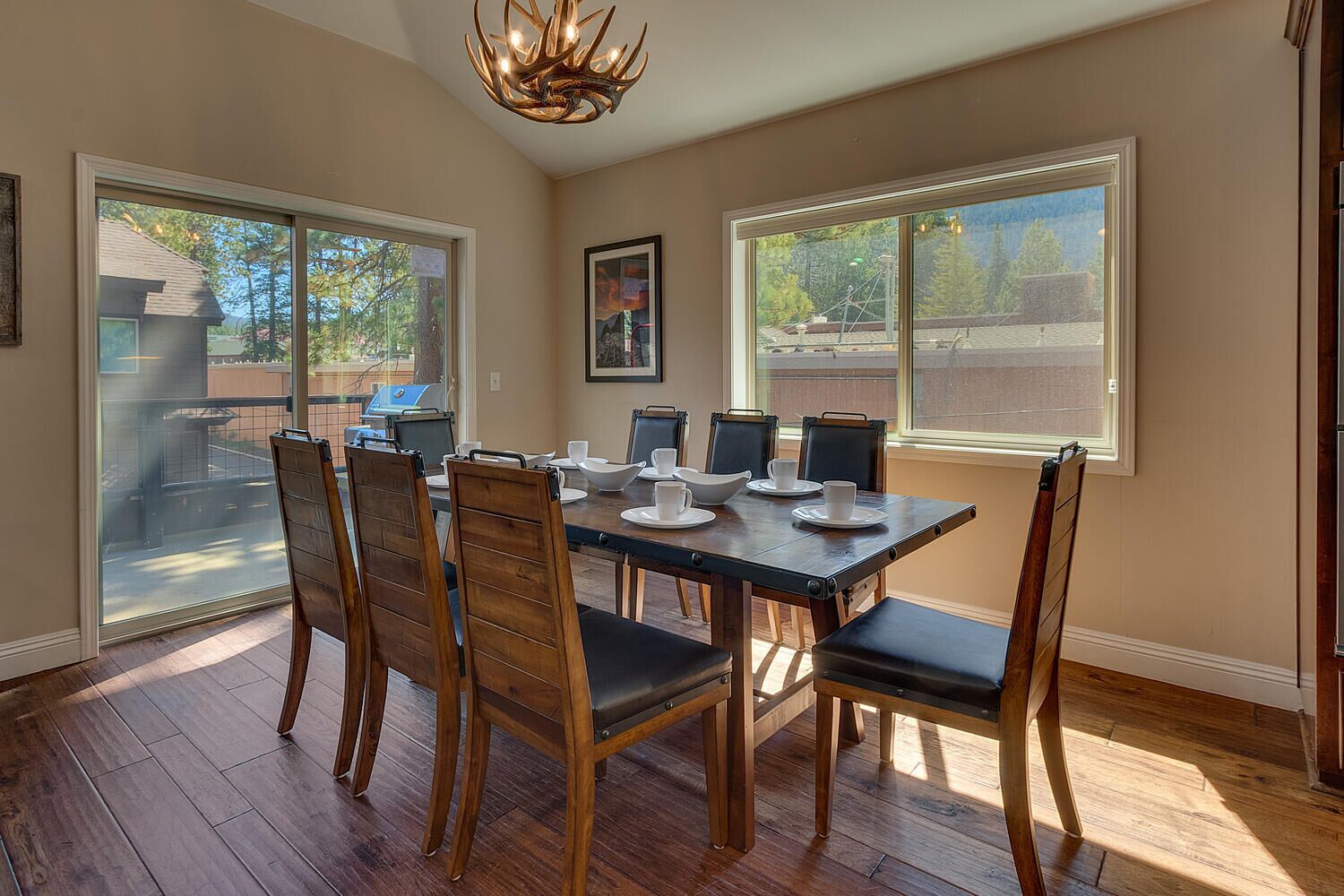 A dining area with a large table, six chairs, and a chandelier.