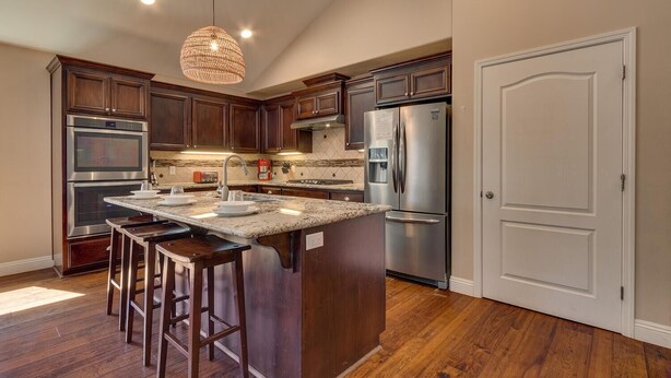 A modern kitchen with dark wood cabinets, stainless steel appliances, and a central island with bar stools. - AC, Batman Arcade, Shuffleboard, 1GB Wifi, Walk to Heavenly/ Lake – Tahoe Woods Retreat (South Lake Tahoe)