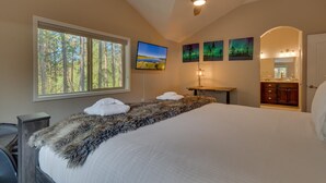 A bedroom with a large bed, a ceiling fan, a TV, and a window with a forest view. - AC, Batman Arcade, Shuffleboard, 1GB Wifi, Walk to Heavenly/ Lake – Tahoe Woods Retreat (South Lake Tahoe)