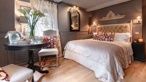 Une chambre bien aménagée, dotée d’un grand lit, d’une table de chevet, d’une chaise et d’une fenêtre avec des rideaux.
